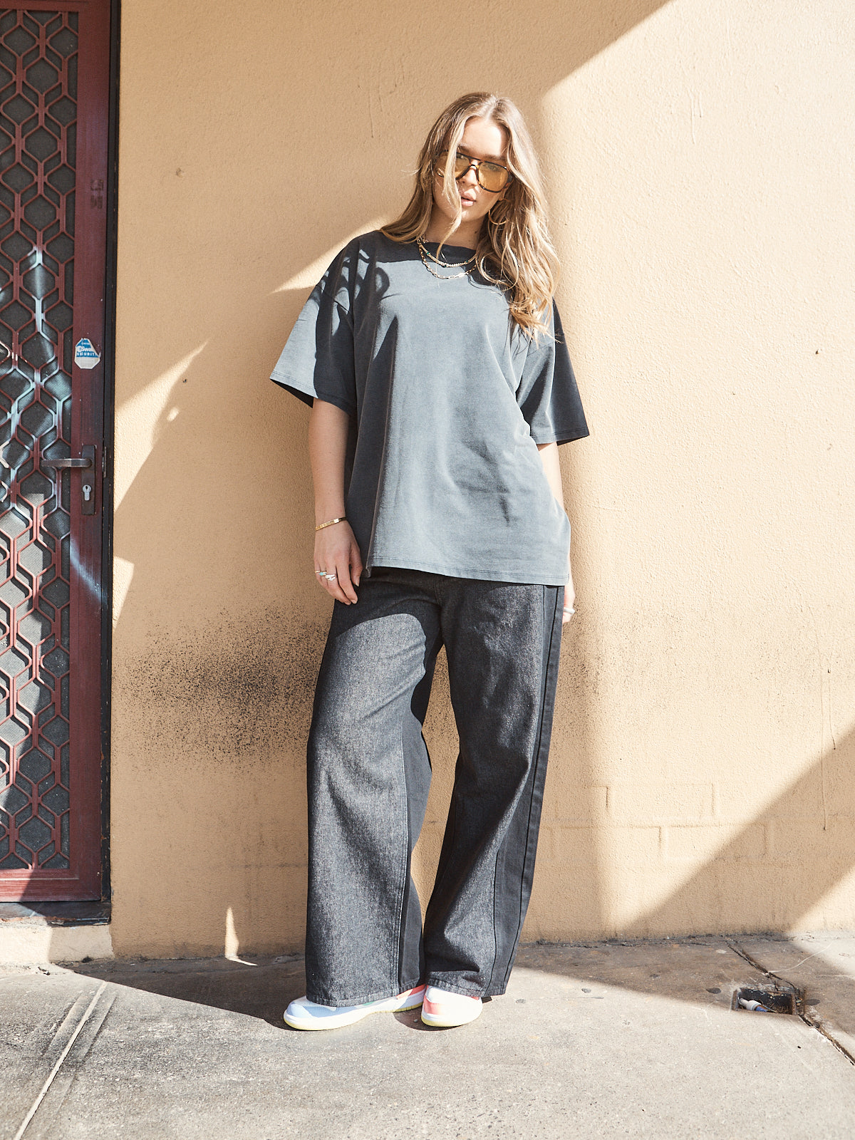 Streetwear outfit featuring oversized washed black t-shirt with woven 72 patch, styled with dark denim pants.